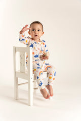 Cute toddler girl wearing a long sleeve T-shirt and slouchy pants set with an adorable bunnies and rainbow print, sitting on a chair and playing, perfect for cozy and playful everyday wear.