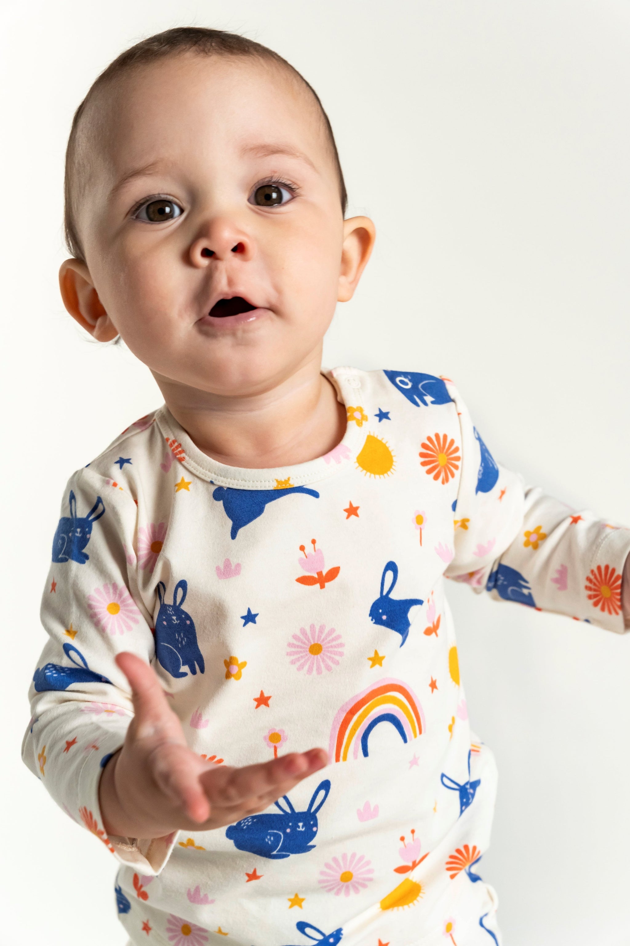 Toddler Girl Long Sleeve T-shirt and Pants Set featuring Bunnies and Rainbow Print. The design includes playful blue bunnies, rainbows, and flowers on a cream background for a fun, cozy look.