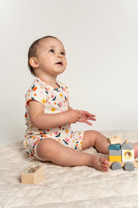 Toddler girl wearing short sleeve t-shirt and slouchy shorts set in Sunny Flower print featuring colorful flowers, suns, and hearts. Comfortable and playful outfit, perfect for everyday wear.