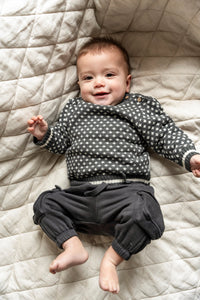 Adorable baby wearing the Nordic Cotton Knit Jumper in a grey and white pattern, made from soft cotton for comfort and warmth. Ideal for chilly days, this sweater adds a cozy and stylish touch to any outfit.