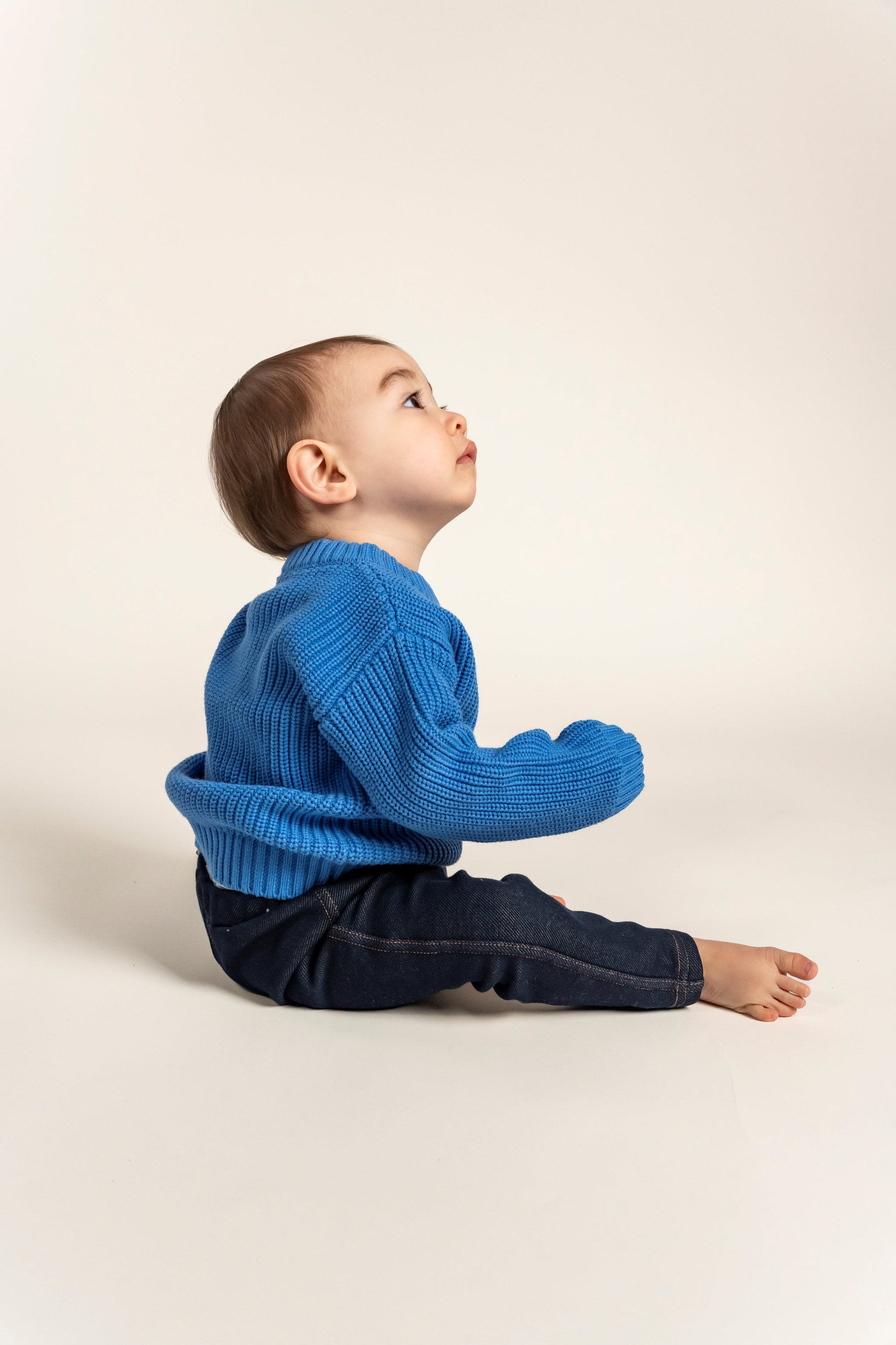 Adorable baby wearing a Sky Blue Cotton Knit Jumper, perfect for keeping little ones cozy and stylish. Made from breathable cotton, this sweater is soft, warm, and ideal for everyday wear. Shop now!