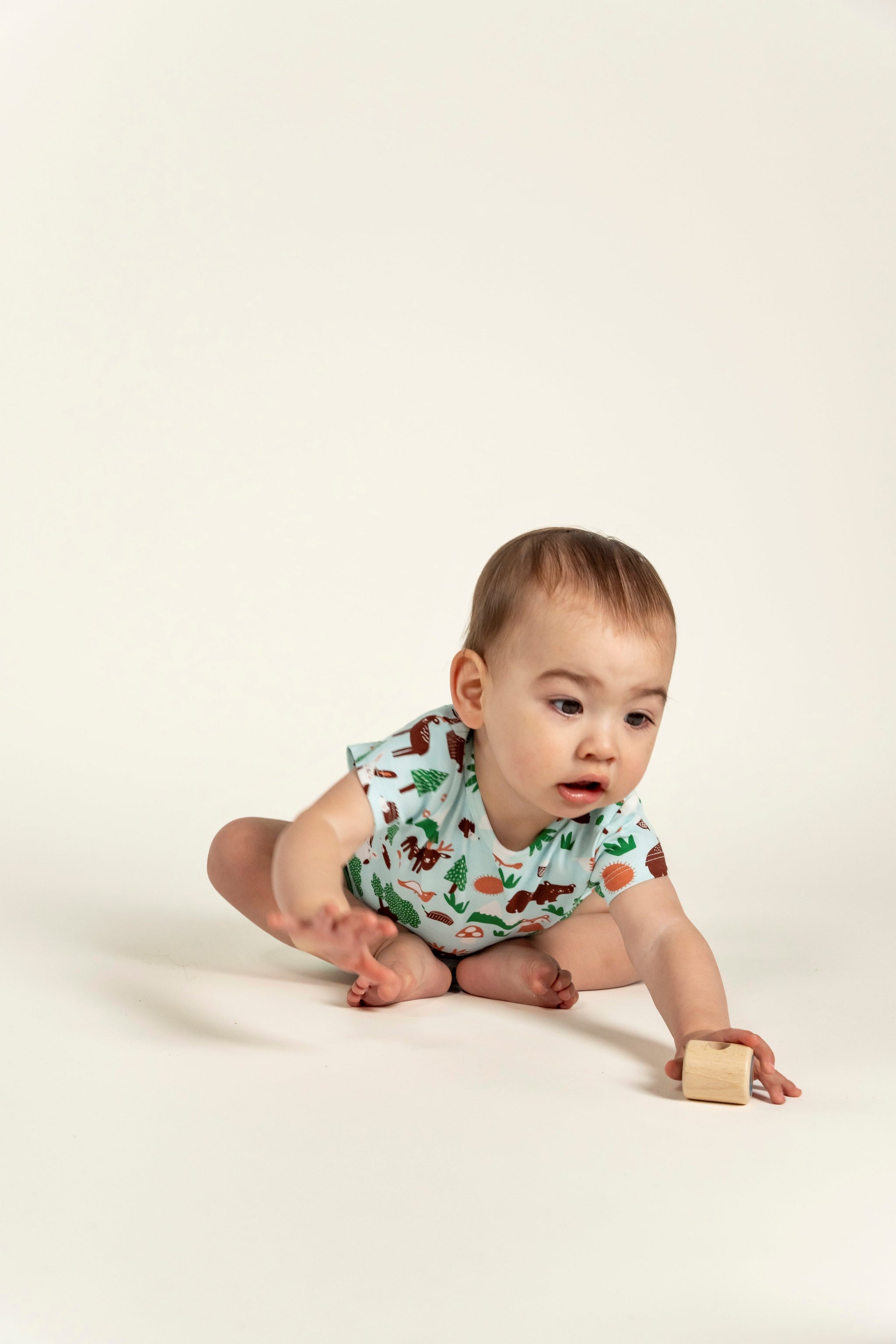 Active toddler boy playing while wearing a short sleeve t-shirt with forest animal print featuring bears, foxes, and trees. Soft, breathable fabric perfect for playtime and everyday comfort.