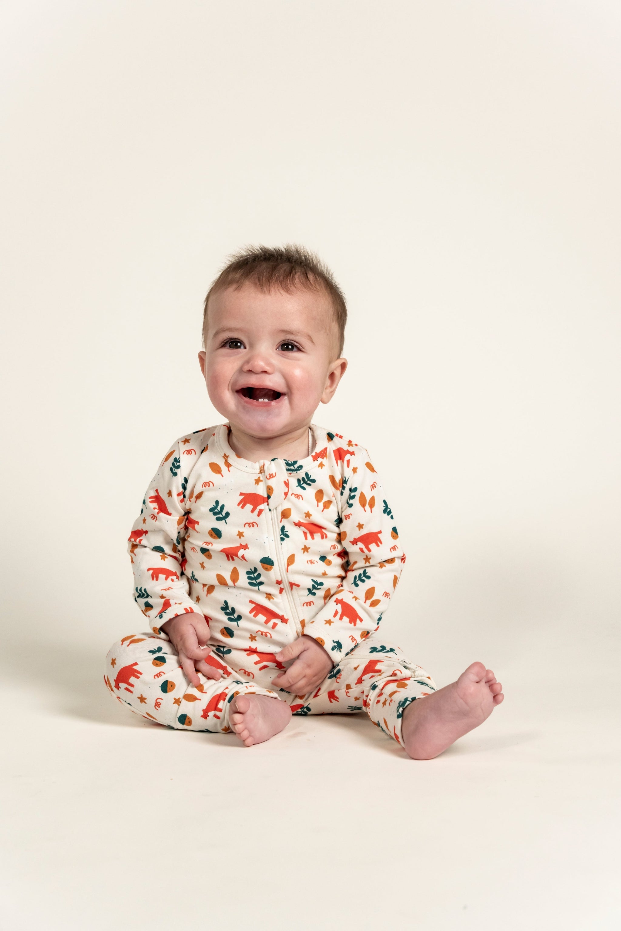 Toddler Boy Long Sleeve Zip Growsuit featuring a playful Fox Forest Print with vibrant orange foxes and green leaves on a cream background. Ideal for cozy sleep or playtime. Perfect for toddlers!