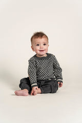 Adorable baby boy in a grey Nordic Cotton Knit Jumper featuring a white geometric pattern. Perfect for keeping your little one cozy and stylish in cold weather. Ideal for winter layering and comfort.