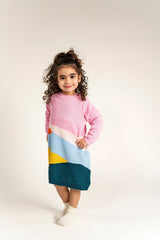 Toddler wearing Serenity Skies Cotton Knitted Sweater Dress with pink sleeves and colorful geometric patterns in blue, yellow, orange, and green. Soft, cozy, perfect for casual fall and winter wear.