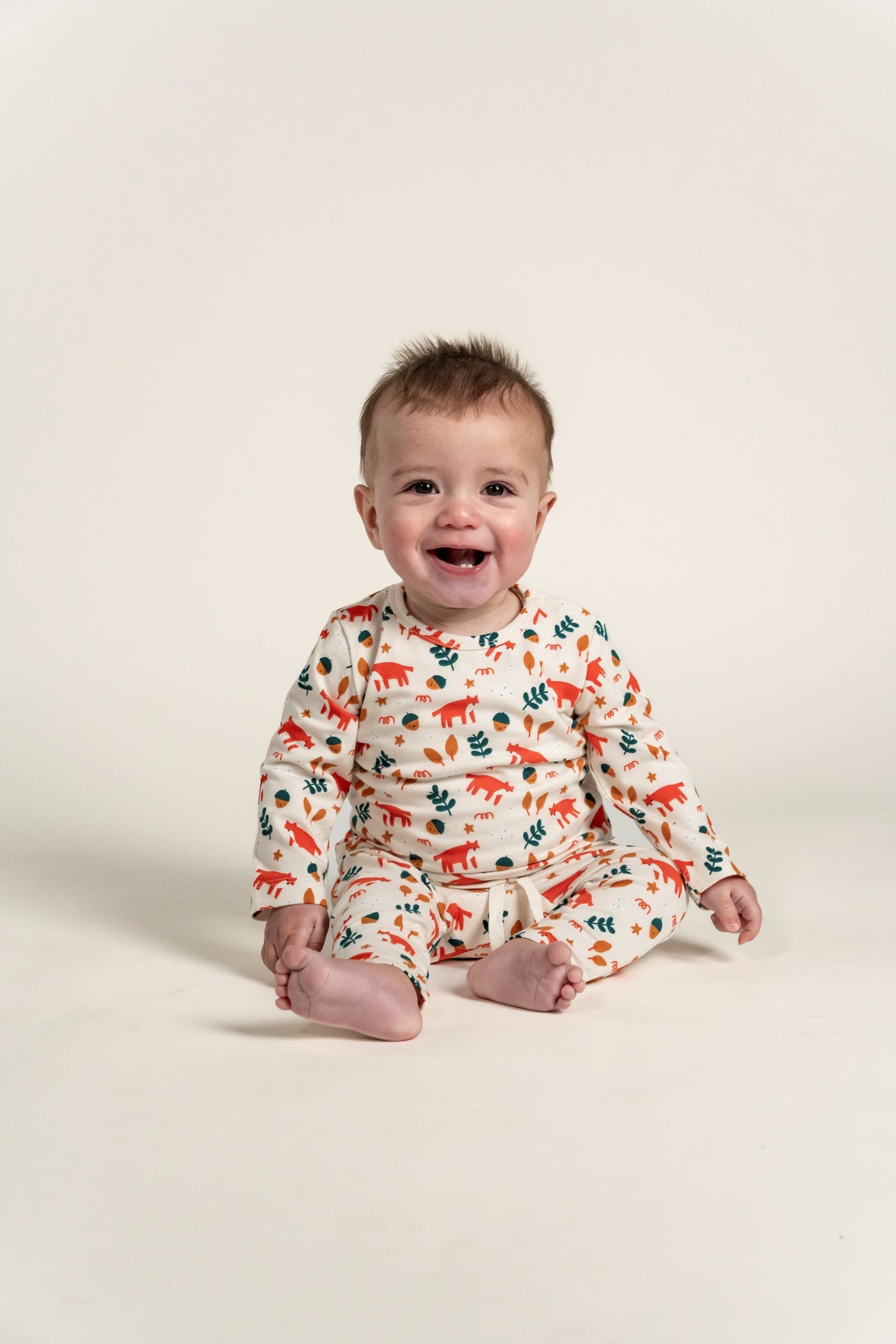 Smiling toddler boy wearing a Long Sleeve T-shirt with a vibrant Fox Forest Print featuring foxes, leaves, and acorns. Comfortable and stylish for outdoor play and casual everyday wear.