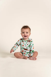 Toddler Boy smiling and sitting while wearing a Long Sleeve Bodysuit with a playful Forest Animal Print. Features woodland creatures like bears, foxes, and trees, perfect for cozy everyday wear.